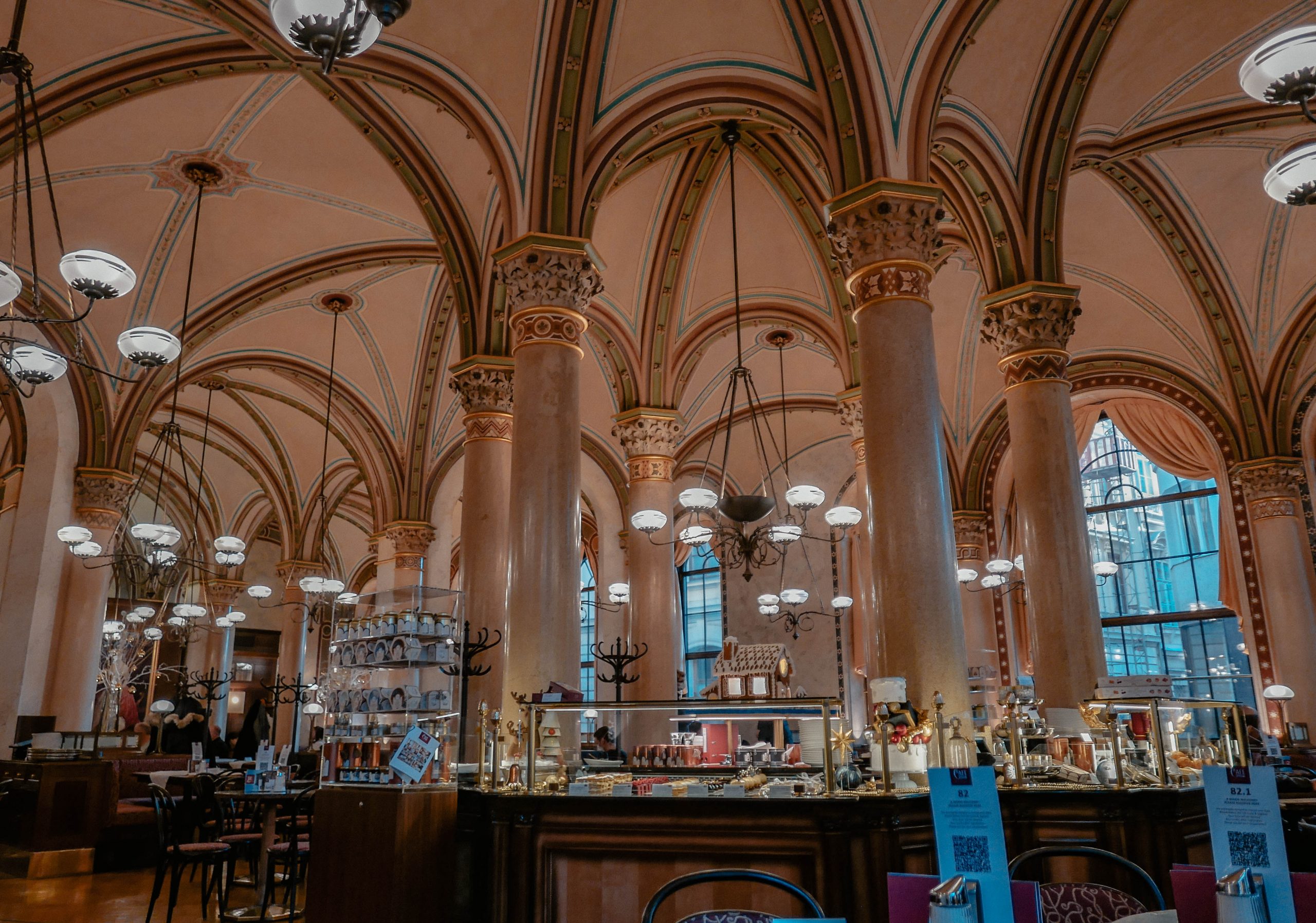 The historic Café Central in Vienna, renowned for its grand vaulted ceilings, intricate arches, and elegant columns, with chandeliers illuminating the lavish interior. Once frequented by notable figures like Sigmund Freud and Leon Trotsky, the café is a symbol of Vienna’s rich intellectual and cultural heritage. The warm lighting and cozy atmosphere invite patrons to experience a piece of history in a refined setting.