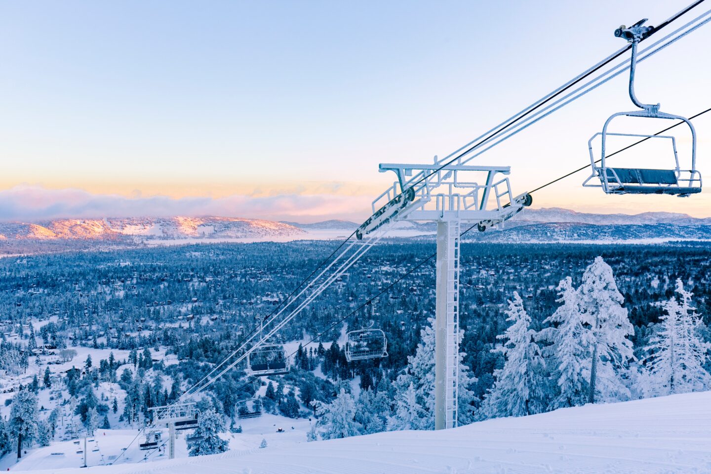 Gondolas against the backdrop of snow-covered mountains in Big Bear California, one of the best beginner-friendly resorts in the USA.
