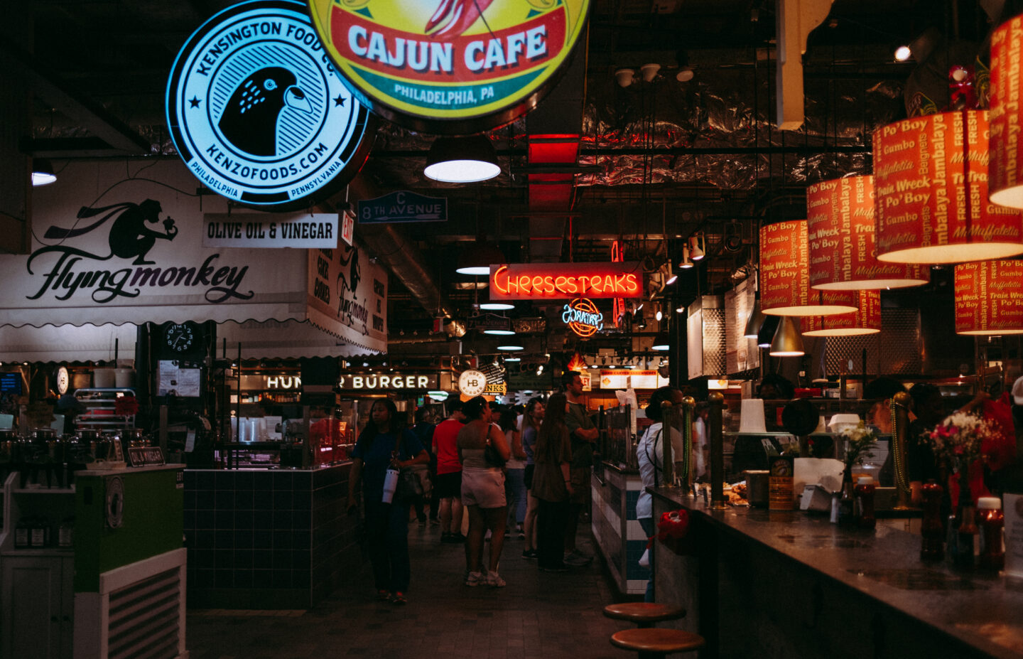 A view of bustling Reading Terminal Market with various stalls and bright neon signs.