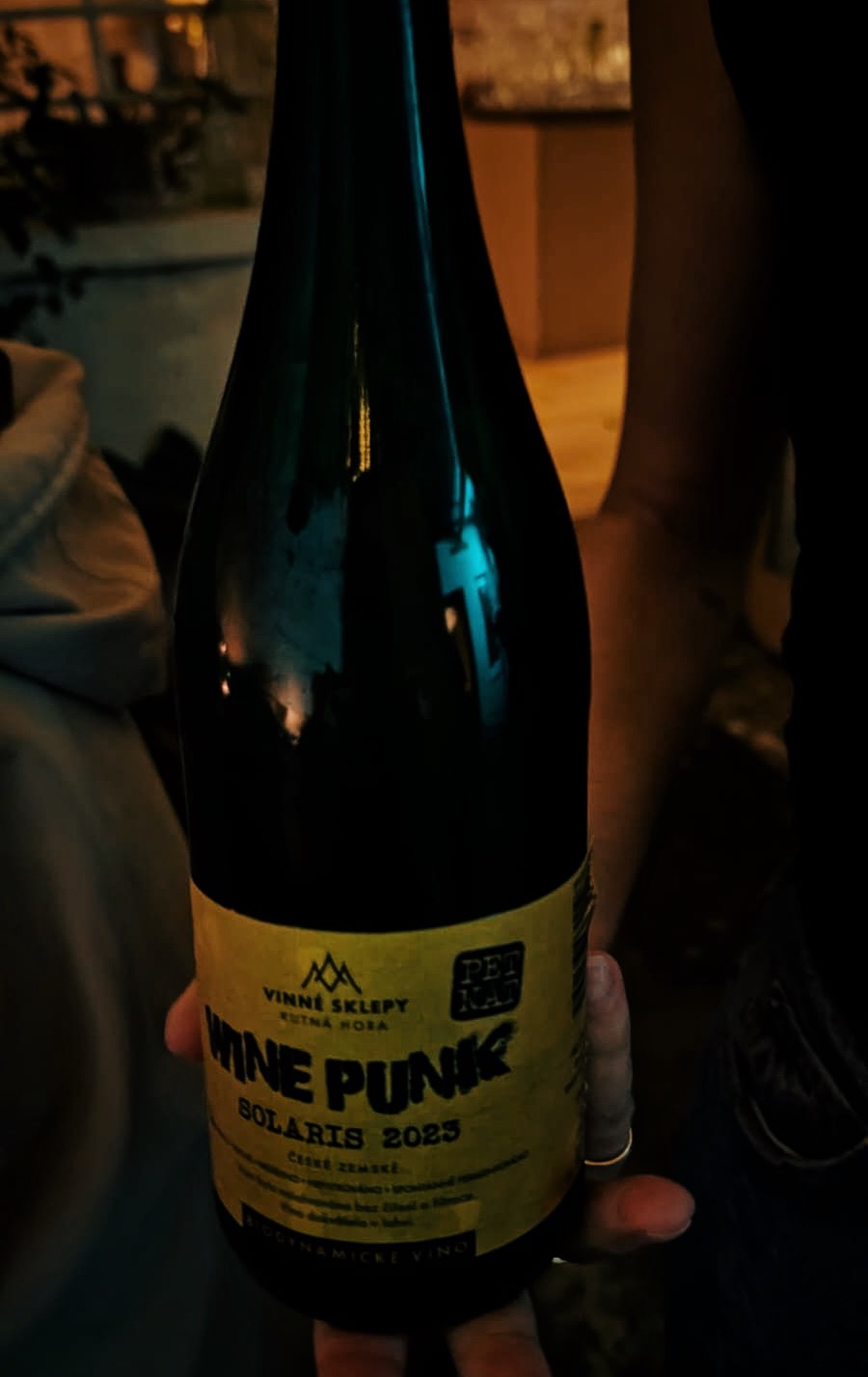 A bottle of Vinné Sklepy Kutná Hora Wine Punk Solaris 2025 held up in the dimly lit Aspen & Meursault wine bar. The yellow label stands out against the dark atmospheric interior.